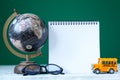 Back to school concept. Yellow school bus toy model and empty blank with globe and school supplies Royalty Free Stock Photo