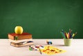 School items on desk with empty chalkboard Royalty Free Stock Photo