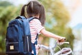 Cute asian child girl with backpack biking a bicycle Royalty Free Stock Photo