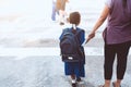 Cute asian pupil girl with backpack holding her mother