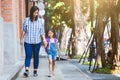 Cute asian pupil girl with backpack holding her mother hand and going to school