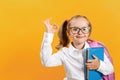 Back to school. A cute little girl with a backpack and a book with glasses shows a sign approx. The concept of success and Royalty Free Stock Photo