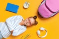 Back to school. A cute little girl with glasses lies on a yellow background. Child book alarm clock backpack brush headphones. Royalty Free Stock Photo