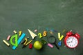 Back to school and education concept with alarm clock, school supplies and green apple on blackboard background top view. Royalty Free Stock Photo