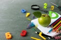 Back to school and education concept with colorful stationery supplies and green apple on blackboard.