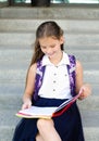 Back to school. Education concept. Cute smiling schoolgirl sitting on a steps outdoor