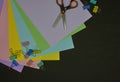 Top view of multicolor paper, paper clips and scissors on dark background with copy space Royalty Free Stock Photo