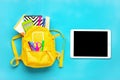 Back to school, education concept. Yellow backpack with school supplies Notebook, pens, ruler, calculator, scissors, tablet