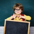 Back to school - education concet. Cute little preschool kid boy in a classroom. School kids against green blackboard.