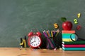 Back to school or education mockup with alarm clock, red apple and stationery supplies against blackboard on wooden table. Royalty Free Stock Photo