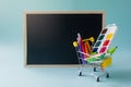 Back to school. Education, sale, office supplies in a grocery cart and a school board on a blue background. Copyspace Royalty Free Stock Photo