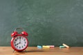 Back to school or education template with alarm clock and colorful chalks against empty blackboard background in classroom. Royalty Free Stock Photo