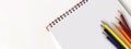 Back to school. Empty notebook and pencils in various colors, on white background.