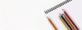 Back to school. Empty notebook and pencils in various colors, on white background.