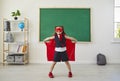 Back to school. Funny schoolgirl superhero standing in class.