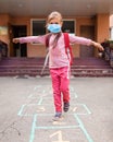 Back to school. A girl in mask jumping and playing hopscotch before school building Royalty Free Stock Photo