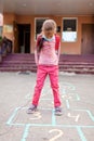 Back to school. A girl in mask jumping and playing hopscotch before school building Royalty Free Stock Photo