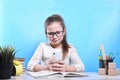 Back to school .Happy cute industrious child is sitting at a desk indoors.Uses a mobile phone for learning.Kid is learning in Royalty Free Stock Photo