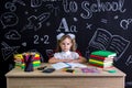 Back to school and happy time. Cute industrious child is sitting at a desk indoors with books, school supplies. Girl Royalty Free Stock Photo