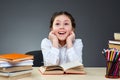 Cute industrious child is sitting at a desk indoors. Kid is learning in class on background of blackboard.