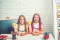 Back to school and home schooling. Friendship of small sisters in classroom at knowledge day. Little girls eat apple at Royalty Free Stock Photo