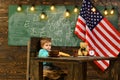 Back to school or home schooling. School kid at lesson in 4th of july. Little boy eat bread at American flag at Royalty Free Stock Photo