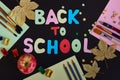 Back to school inscription made of colored letters, school supplies, ripe red apple and autumn leaves on the black background. Royalty Free Stock Photo