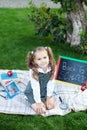 Back to school. The kid is ready for school. smart child a little girl with school supplies sits on a lawn: a school board, books, Royalty Free Stock Photo