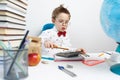 Back to school: a little boy in a shirt and glasses sits at his desk and does the calculations on a calculator. Royalty Free Stock Photo