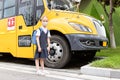 Back to school. Little girl from elementary school outdoor near yellow bus. Kid going learn new things 1th september Royalty Free Stock Photo