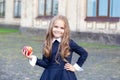 Back to school. A little girl of preschool age stands with an apple on her first day at school or kindergarten. little schoolgirl Royalty Free Stock Photo