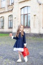 Back to school. A little girl of preschool age stands with a backpack and an apple on her first day at school or kindergarten. Lit