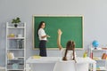 Back to school. Little girl raising hand to answer her teacher at math lesson. Royalty Free Stock Photo