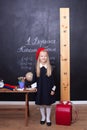 Back to school! little girl at school is standing near the table. School concept. Schoolgirl answers the lesson. On the blackboard Royalty Free Stock Photo