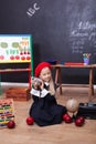 Back to school! A little girl sits in a lesson with a clock in her hands. Schoolgirl responds to the lesson. The kid is studying i Royalty Free Stock Photo