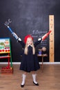 Back to school! A little girl stands with large pencils in her hands at school. School Girl responds to the lesson. On the blackbo Royalty Free Stock Photo