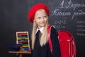 Back to school! Little girl stands in school with a red backpack. Schoolgirl responds to the lesson. The kid is studying in the cl Royalty Free Stock Photo