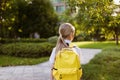 Back to school. Little girl with yellow backpack from elementary school outdoor. Kid going learn new things 1th Royalty Free Stock Photo