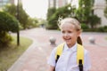 Back to school. Little girl with yellow backpack from elementary school outdoor. Kid going learn new things 1th Royalty Free Stock Photo