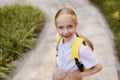 Back to school. Little girl with yellow backpack from elementary school outdoor. Kid going learn new things 1th Royalty Free Stock Photo