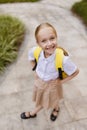 Back to school. Little girl with yellow backpack from elementary school outdoor. Kid going learn new things 1th Royalty Free Stock Photo