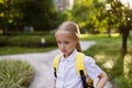 Back to school. Little girl with yellow backpack from elementary school outdoor. Kid going learn new things 1th Royalty Free Stock Photo