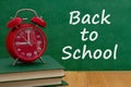Back to School message with alarm clock on books with a chalkboard Royalty Free Stock Photo