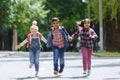 Back to school. Mixed Racial Group of happy elementary school students with backpacks running holding hands outdoors