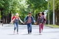 Back to school. Mixed Racial Group of happy elementary school students with backpacks running holding hands outdoors