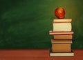 Back to school, pile of books and red apple with empty green school board background, education concept Royalty Free Stock Photo