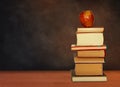 Back to school, pile of books and red apple with empty green school board background, education concept Royalty Free Stock Photo