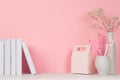 Back to school pink girl`s background - white stationery, books and lunch box on white wood table and pastel pink wall.