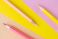 Back to school. Pink and yellow pencils lie on the same colors background.