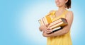 Back to school. Portrait of a happy smiling woman holding a stack of books. Blue background. Copy space. Concept of education and Royalty Free Stock Photo